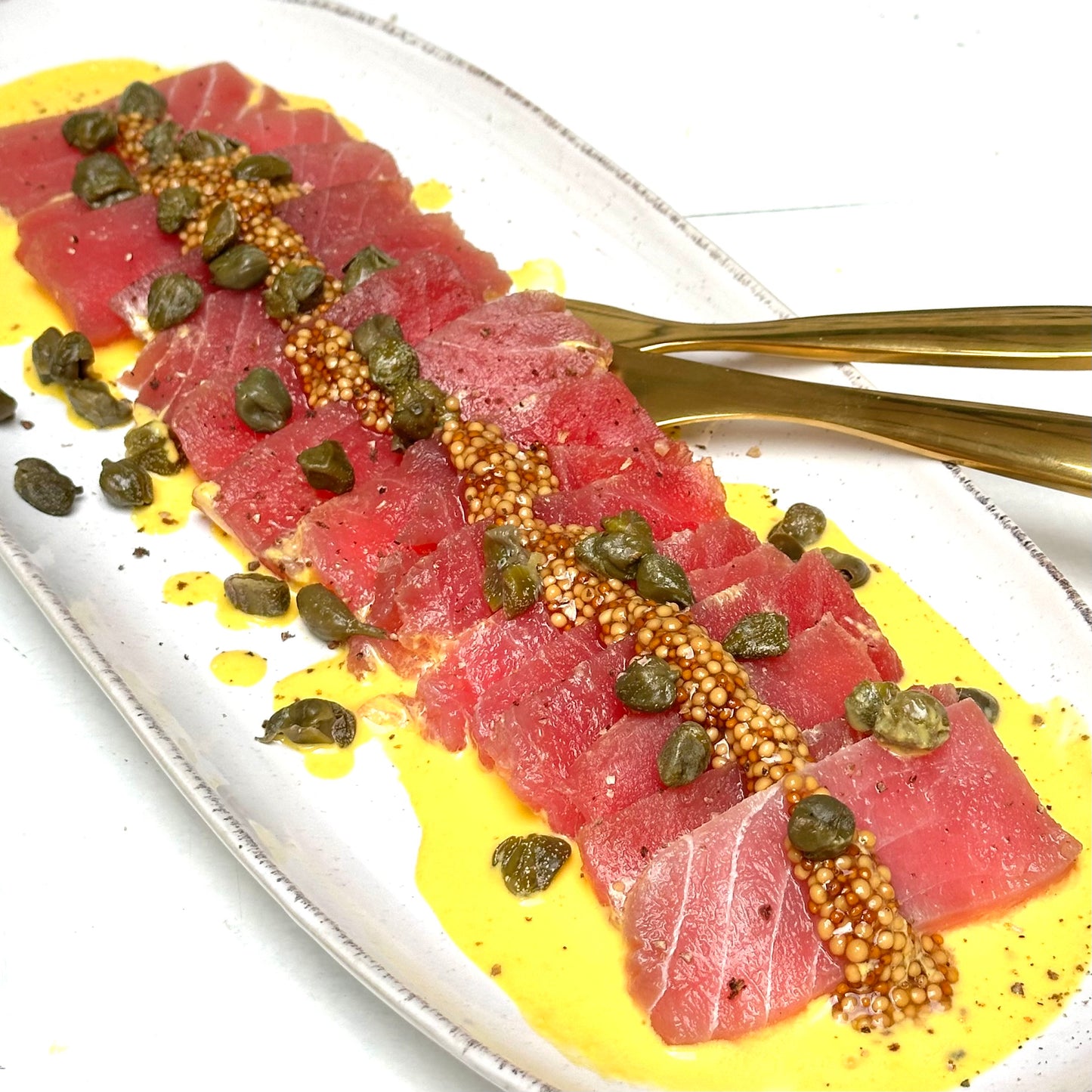 Tiradito de atún con salsa huancaína, mostaza encurtida y alcaparras fritas