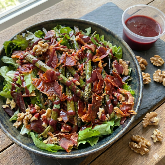 Ensalada verde con espárragos salteados, jamón serrano crocante, nueces acarameladas y aliño de moras y oporto